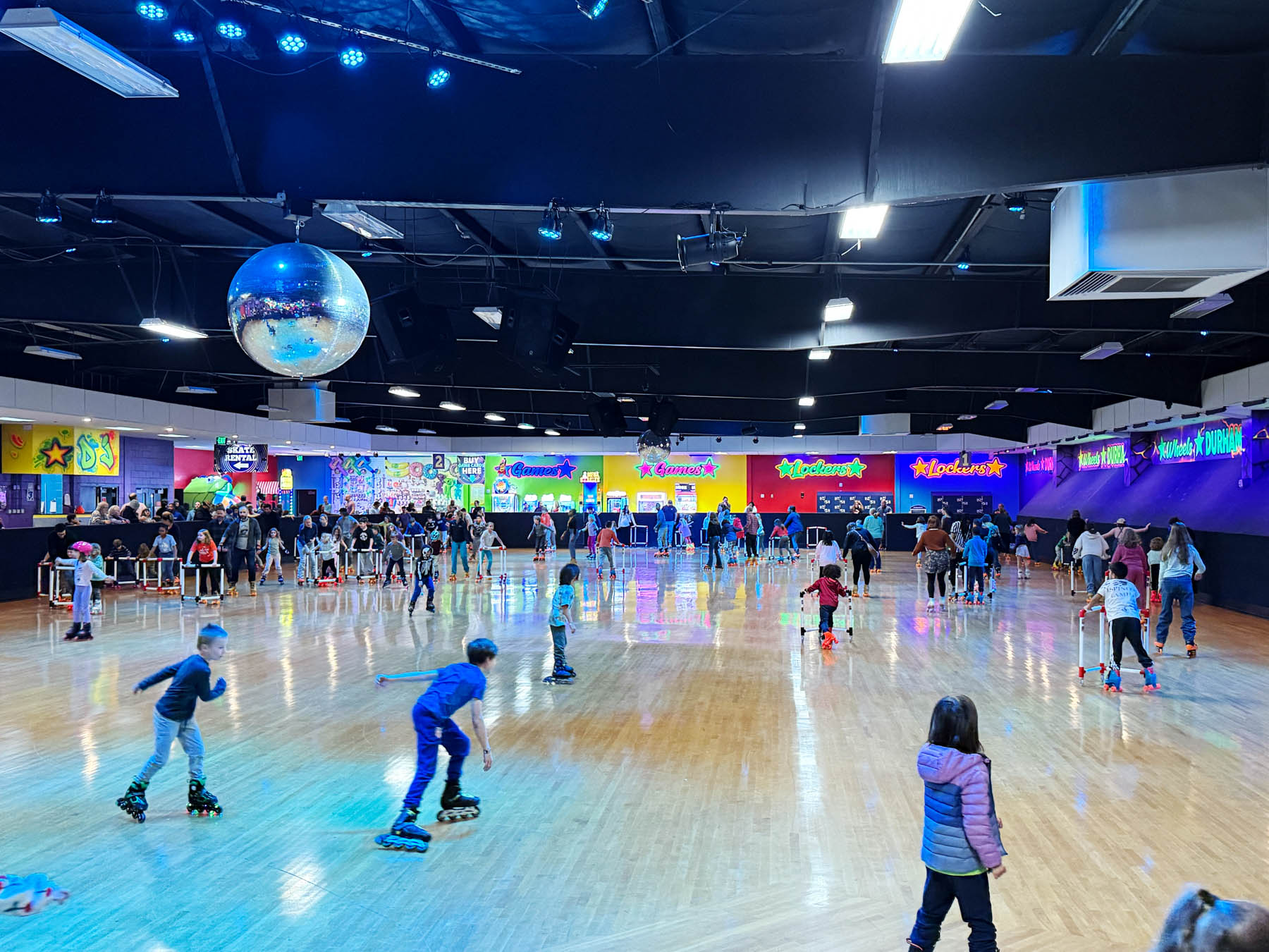 Children and adults skate around the indoor roller skating rink at Wheels Fun Park in Durham