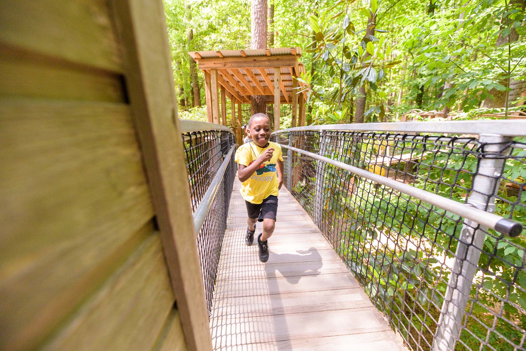 Young boy runs across a bridge at the Museum of Life and Science in Durham