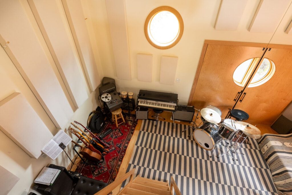 Overhead view of a recording studio with instruments, acoustic panels and a ladder leading to a loft.