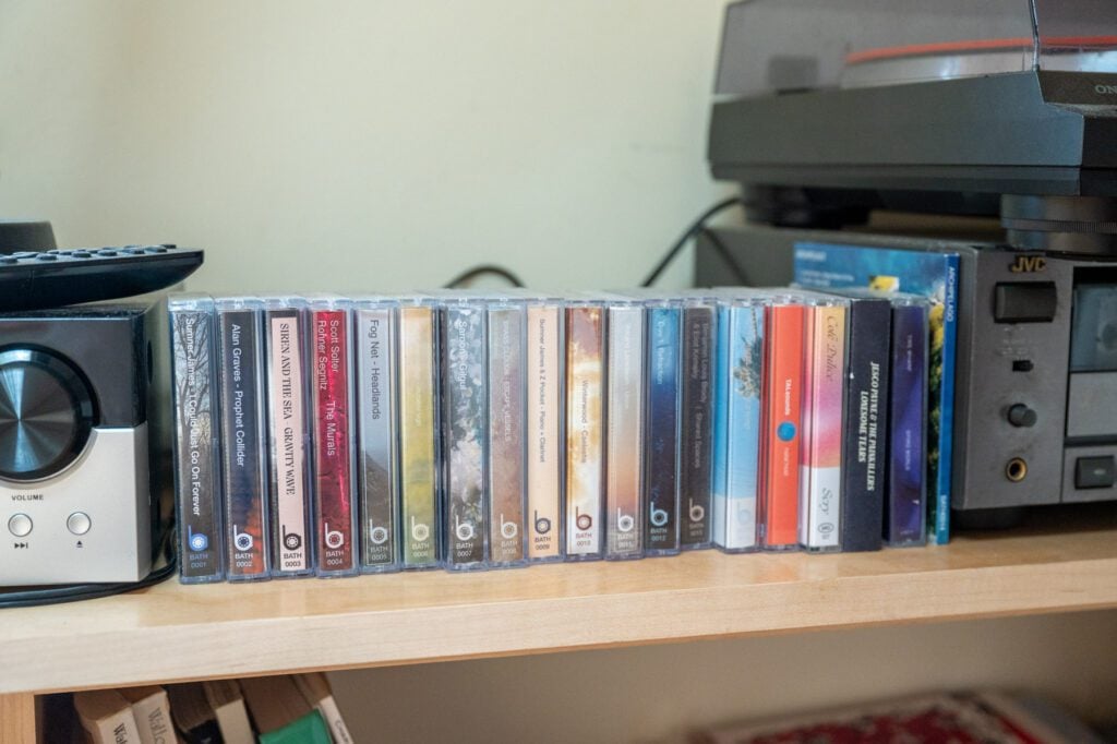Row of cassette tapes on a shelf next to a stereo and record player.