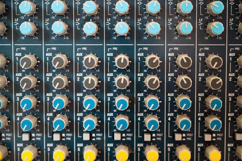 Close-up of a recording studio mixing console with rows of knobs and controls.
