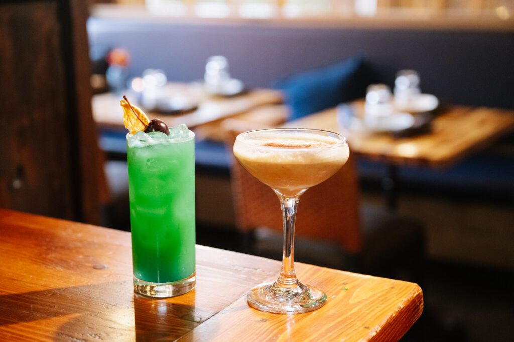 Green Mermaid’s Cove cocktail and an espresso martini on a bar at Nerra.