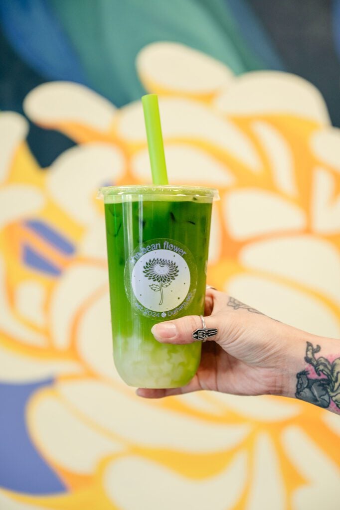 Matcha latte from The Bean Flower in Durham, held by the owner, CC Chu, for a photo.
