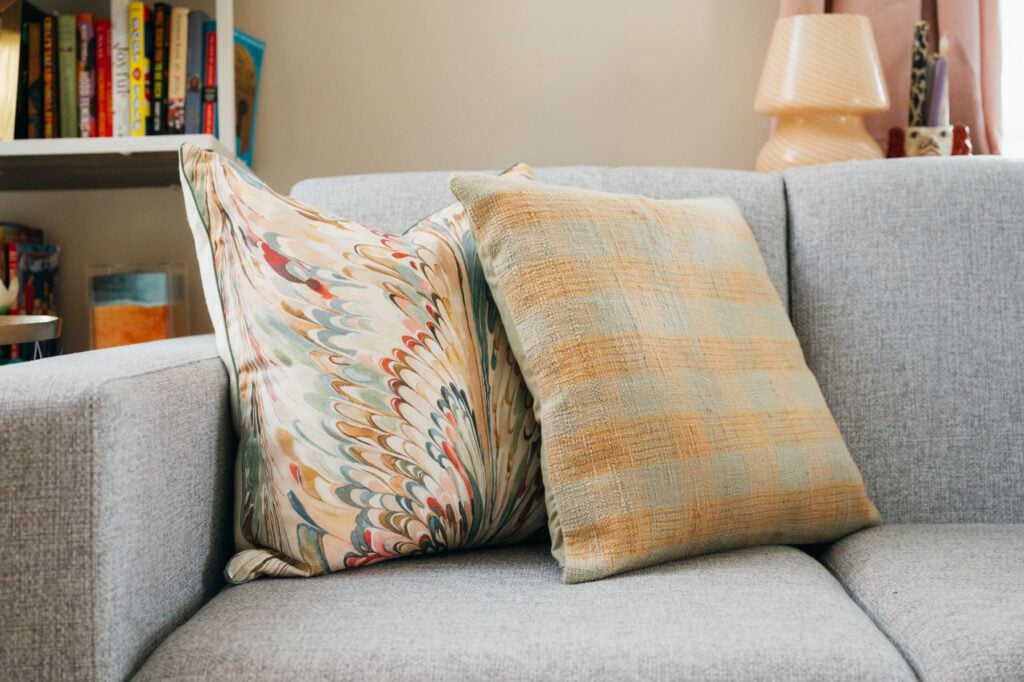 Decorative throw pillows from Vintage Home South and The Borough styled on a light gray sofa in Courtney Hayes’ living room.