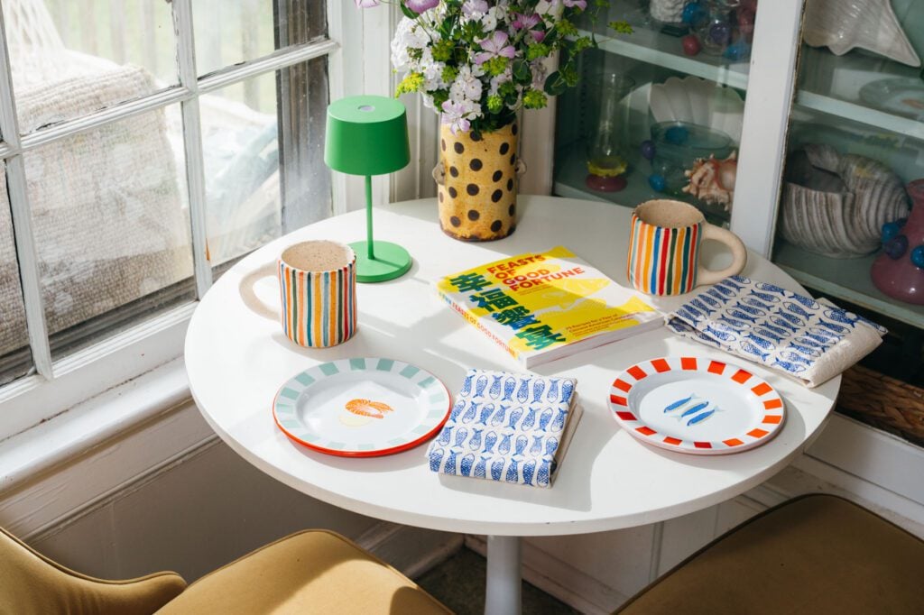 Colorful table setting with mugs, enamel plates and a cookbook from Indio and The Borough in Courtney Hayes’ breakfast nook.