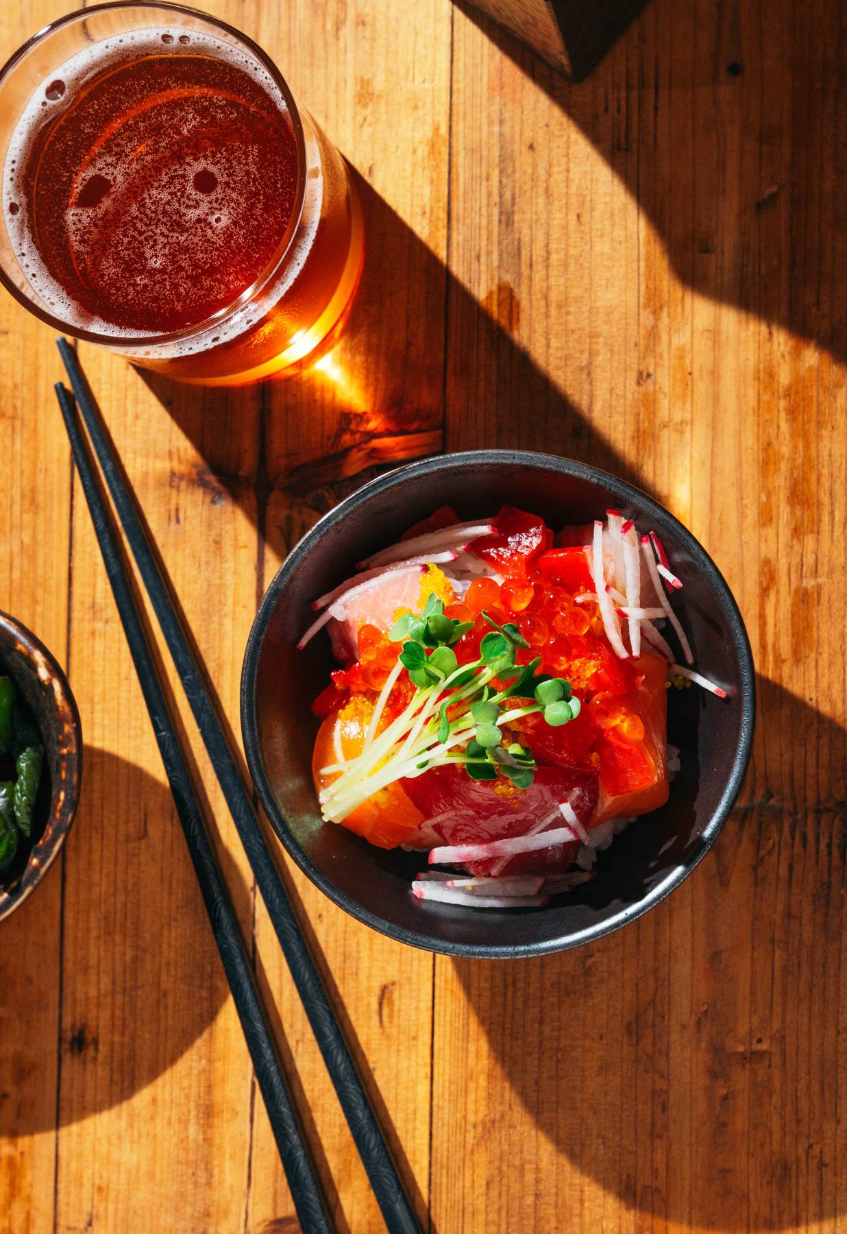 The chirashi bowl from M Sushi sits with a drink and chopsticks.