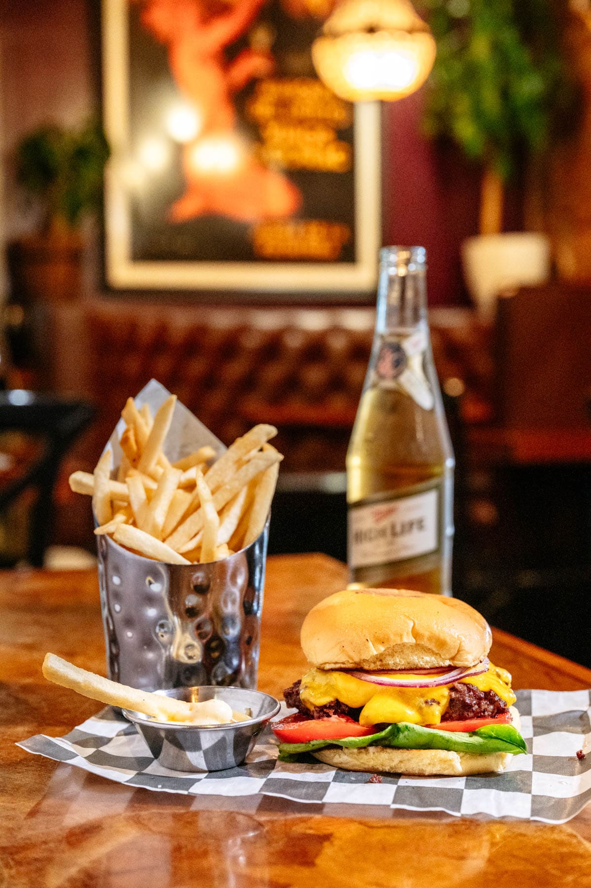 A burger, French fries and a beer sit on a table at Bar Virgile.
