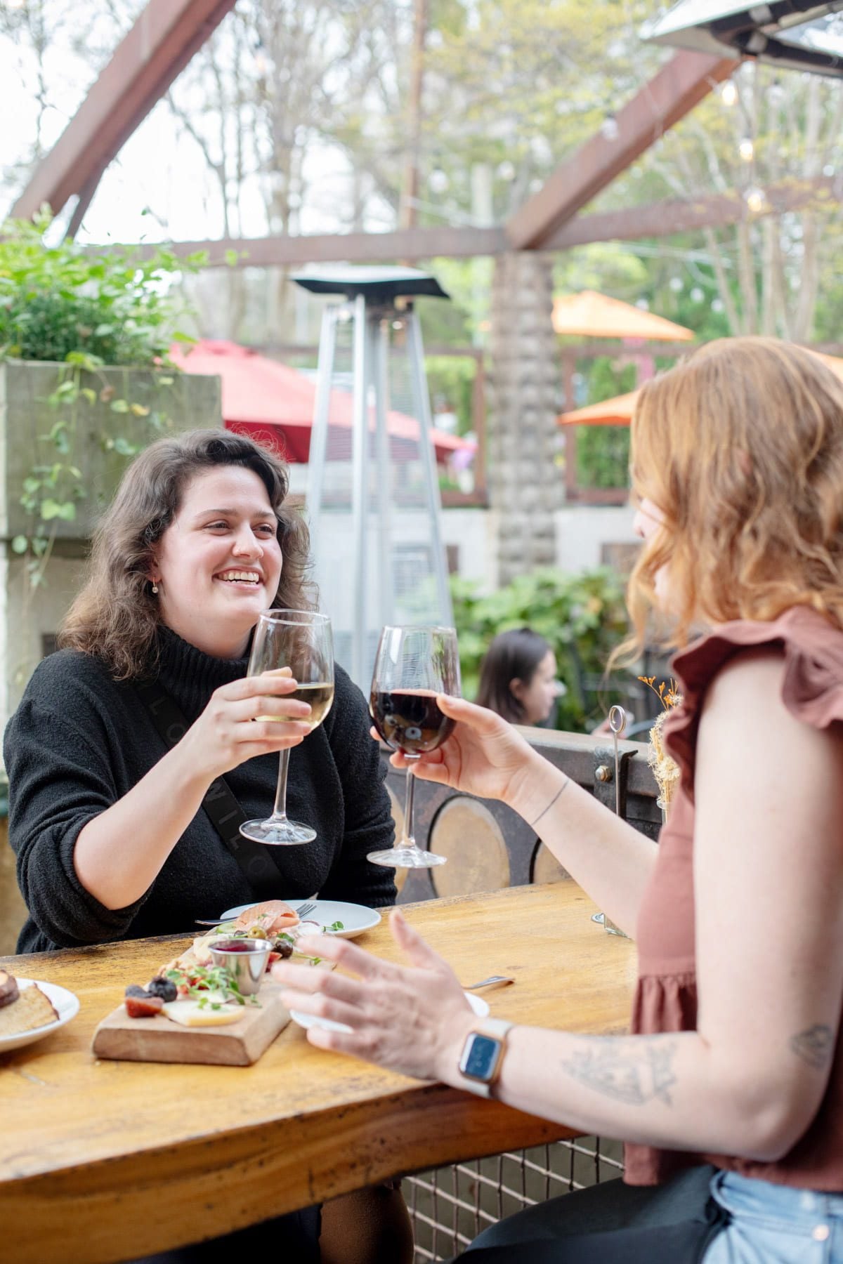Two women share a glass of wine and food on the patio at Guglhupf Bakery & Restaurant.