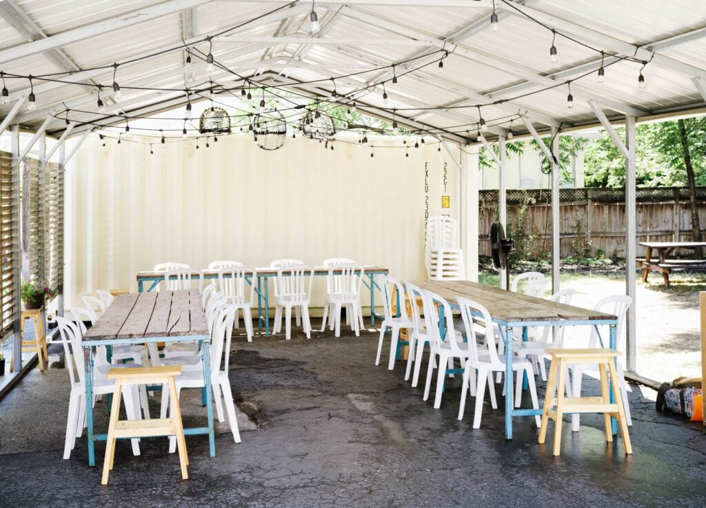 Durham's Jean's "By the Sea" bright covered patio with string lights, wooden tables and white chairs.