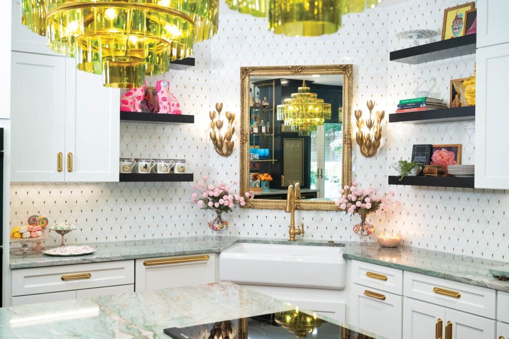 An ornate mirror that once belonged to Allie’s parents hangs above the kitchen sink, while brass bar hardware and a cabinet screen add thoughtful finishing touches to the room. The room carries brass accents with a white background.